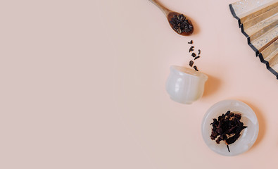 Chinese tea party. Dry granules of different types of tea in a white stone Cup, in wooden spoons on a delicate pink background. background is decorated with Oriental fan with space for text