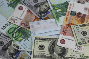 Medical mask among the different denominations , dollars, euros and Russian rubles. Coronavirus as the cause of the global financial crisis in the spring of 2020