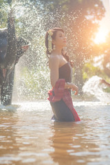 Beautiful thai women wearing traditional thai clothes standing on an elephant in nature park thailand, woman concept