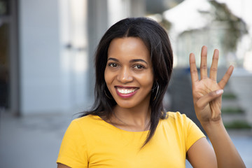 Black African woman pointing, counting four finger; portrait of positive happy smiling black...