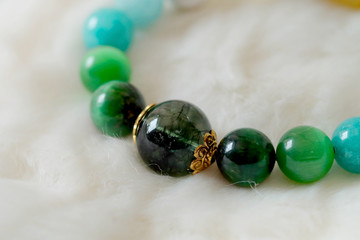 Green and white tone lucky stone bracelet. green moss agate, Green tiger's eye, jade on white wool background. supplement Fortify Fortunate charm and rich