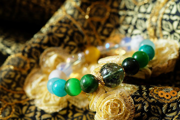 Green and white tone lucky stone bracelet. green moss agate, Green tiger's eye, jade on Thai traditional golden tone fabric background. supplement Fortify Fortunate charm and rich