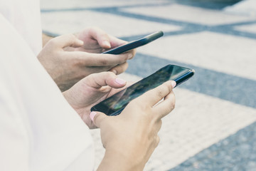 Couple texting messages outside. Hands of young man and woman using smartphones together. Digital communication concept