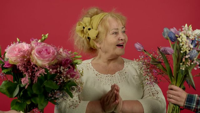 Cheerful senior woman looking at bouquets and holding eustoma flowers with smile