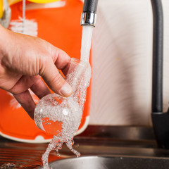 A man pours tap water into a glass flask.