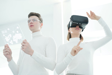 Below view of young developers synchronizing virtual reality simulator and futuristic tablet