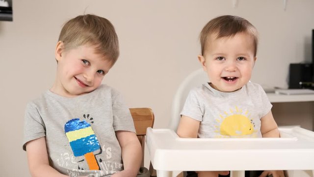 Siblings boys smiling and laughing when looking at camera. Portrait of baby and his brother at home