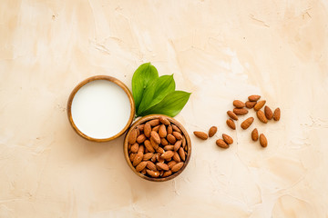 Almond milk near nuts on beige background top-down