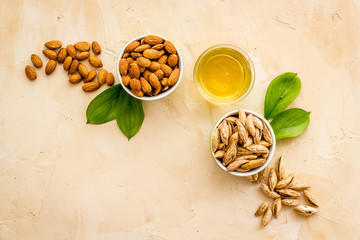 Almond oil - for cooking - in glass bowl near nuts on beige background top-down
