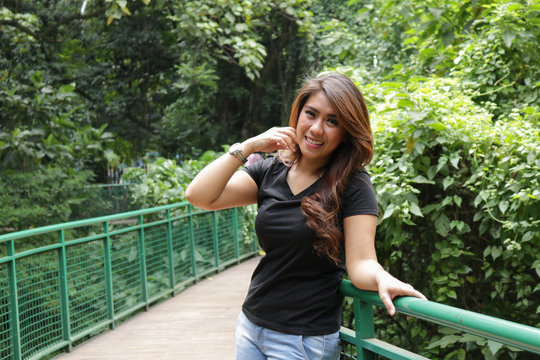 Young female wearing black t shirt and posing in the park. Suitable for mock up design template.