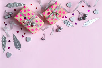 Gifts decorated by silver hearts, ribbon, silver Australian native eucalyptus leaves and gum nuts, pink heart glitter on a pink/purple background background. Romantic cute love flatlay.
