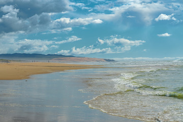Sandy beach and ocean view. Beautiful mountains and cloudy sky on background. Pacific Ocean, California Coast