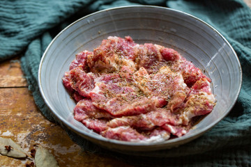 Fresh-marinated raw steak with Vanilla and pepper in bowl on wooden background.
