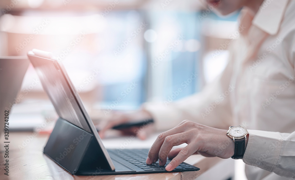 Poster cropped shot of businessman using and typing on computer keyboard while sitting at office desk.