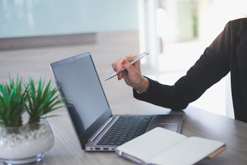 Close up hands of businesswoman using pen to point the screen of laptop.