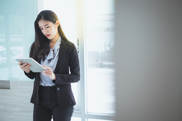 Young businesswoman is standing and holding tablet while she is analyzing business data.