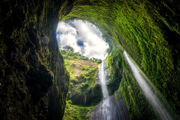 Beautiful view of Madakaripura waterfall with green moss and blue sky in Java, Indonesia.