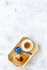 Breakfast with summer flowers. Tea, croissant and cornflowers on light background top-down copy space