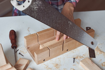 Process of carpenter hands sawing a wooden board. Concept of DIY woodwork and furniture making