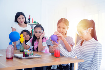 Group of young asian schoolgirls doing experiment in chemistry classroom.