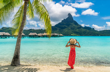 Luxury beach vacation travel destination tourist woman walking on Bora Bora island enjoying holiday in Tahiti, French Polynesia with Mount Otemanu and overwater bungalows villas hotel landscape.
