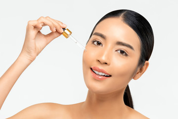 Obraz na płótnie Canvas Beautiful Asian woman applying anti aging moisturizing serum on her face for beauty and skin care concepts