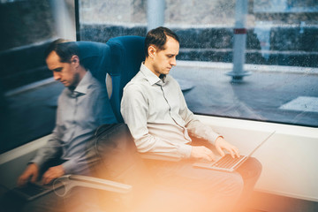 Man working on laptop at the train. Businessman traveling on train.