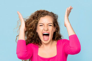 Shocked angry young Caucasian woman shouting isolated on light blue studio background - obrazy, fototapety, plakaty
