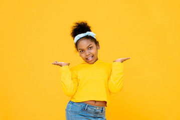Young cute African American mixed race girl smiling and doing open palms gesture isolated on colorful yellow background