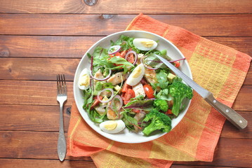 Chicken salad with avocado and cherry tomatoes, arugula and beet leaves. Healthy lunch bowl with vegetables and chicken on a wooden background. Healthy food concept