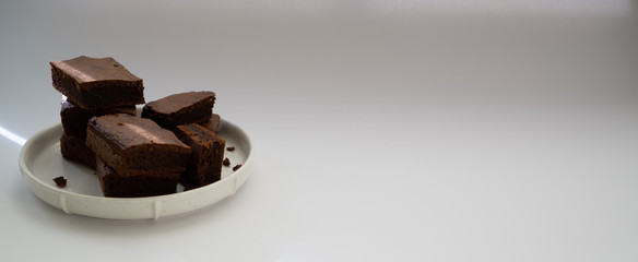 Chocolate brownie sliced into square slices on a white plate.