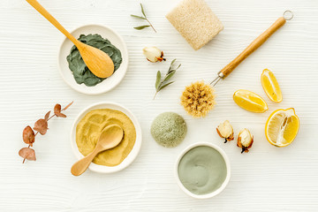 Clay mask, natural facial cosmetic set with herbals on white background - top view
