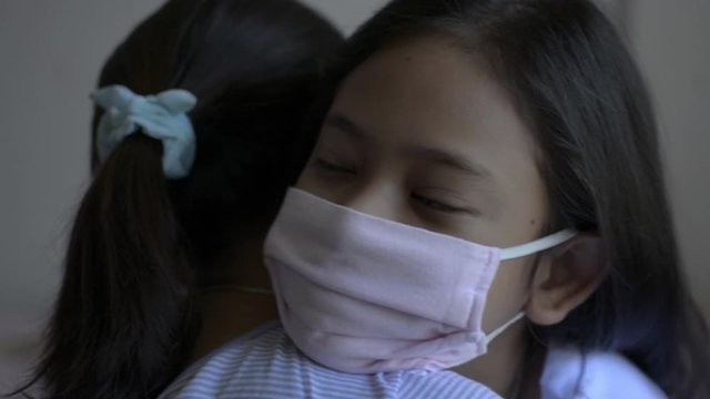 Mother and her daughter hugging each other and wearing protective mask during COVIC 19 outbreak situation. Corona virus protection. Healthy and safety life concept. Expression of love.