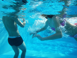 Bodies of people swimming in a pool under water. Blue