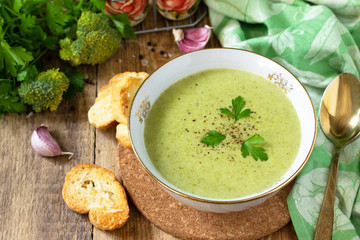 Vegetarian dish. Delicious broccoli cream soup served with croutons on a rustic table.