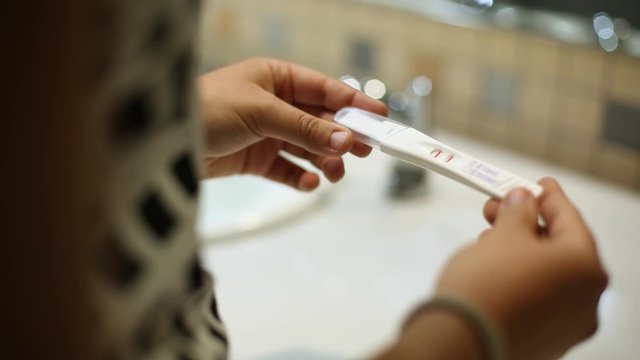 Close Up Tracking Of Woman Holding Positive Pregnancy Test In Public Bathroom