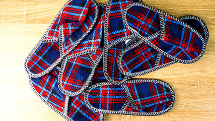 A lot of colorful comfortable, cushioned, checkered disposable slippers are on the wooden floor. Top view. Concept of hospitality. Close-up.