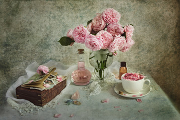Still life with pink rose flowers, glass bottle and box on light blue background