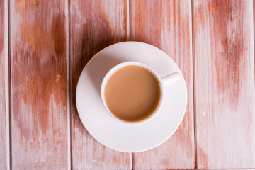 Fragrant coffee with milk on a wooden table in a white cup.