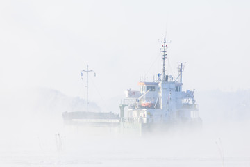 Freight boat in mist. Göta Älv river, Sweden