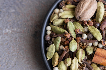 Garam masala in black plate on cocrete background. Indian blend of ground spices used in Oriental cuisine and in Ayurvedic medicine.Top view.Copy space