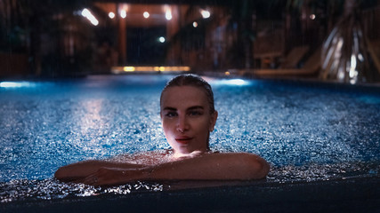 Portrait of girl in swimming pool with blue water at night
