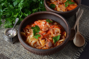 Cabbage stew with grilled sausage in tomato sauce - traditional dish of German, Polish or Russian cuisine