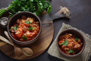 Cabbage stew with grilled sausage in tomato sauce - traditional dish of German, Polish or Russian cuisine