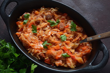 Cabbage stew with grilled sausage in tomato sauce - traditional dish of German, Polish or Russian cuisine