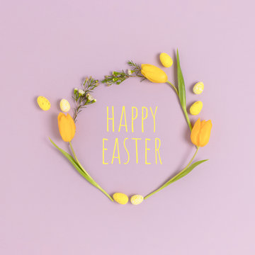 Wreath Made Of Eggs And Flowers On A Purple Pastel Background. Quote Happy Easter. Holiday Concept.