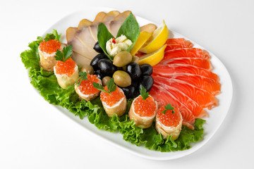Plate with appetizer of fish and seafood. Sliced salted fish fillet. Smoked herring, salmon, perch, olives and lemon. Banquet festive dishes. Gourmet restaurant menu. White background.