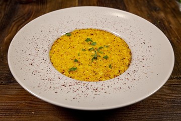 Close up and over a plate of risotto with saffron, white plate on a rustic  table