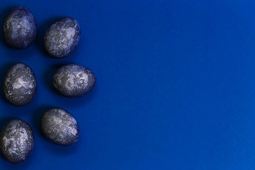Eggs with marble stone effect painted with natural dye carcade flower on blue sparkling background