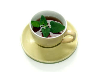 Clay beige cup of hot tea with mint leaves isolated on a white background.